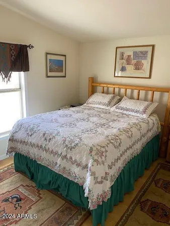 a bedroom with a bed painting on the wall and a window