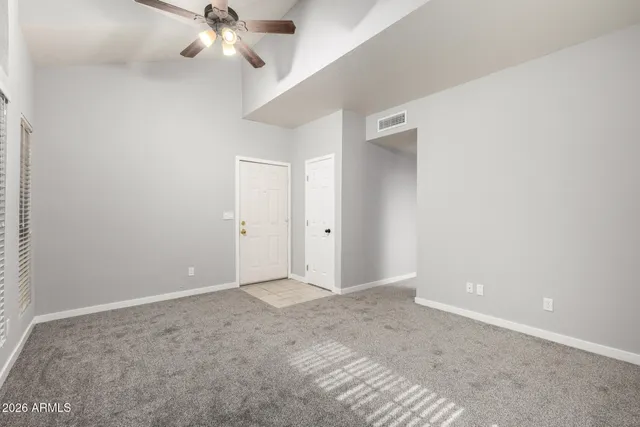 a view of an empty room with a chandelier fan