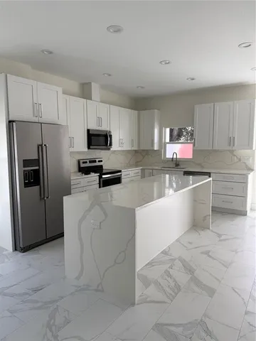 a kitchen with stainless steel appliances a refrigerator sink and microwave