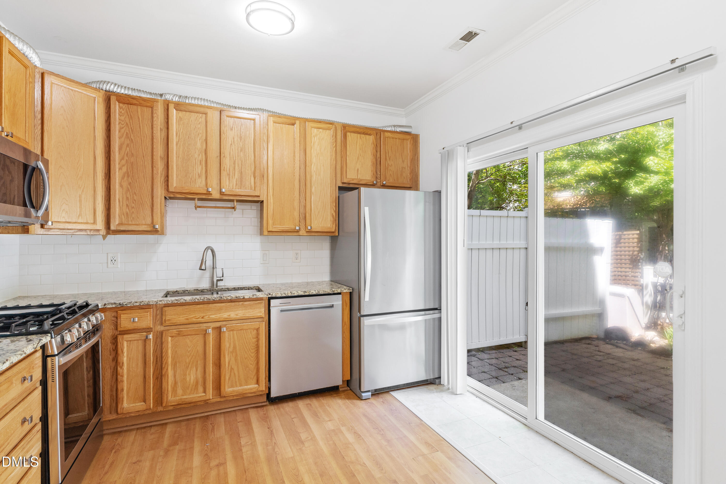11710 Mezzanine Drive, Unit 101 Raleigh, NC 27614 - Photo 13 of 29 a kitchen with stainless steel appliances granite countertop a refrigerator a sink and white cabinets with wooden floor