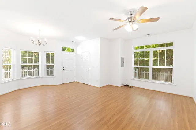 a view of an empty room with a window and wooden floor