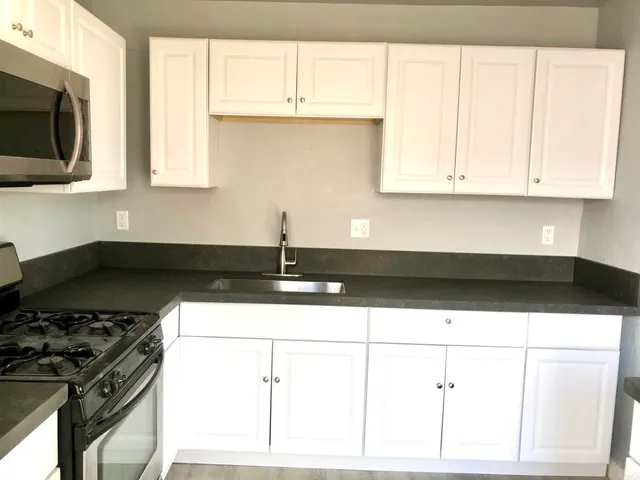 a kitchen with stainless steel appliances a sink a stove and white cabinets