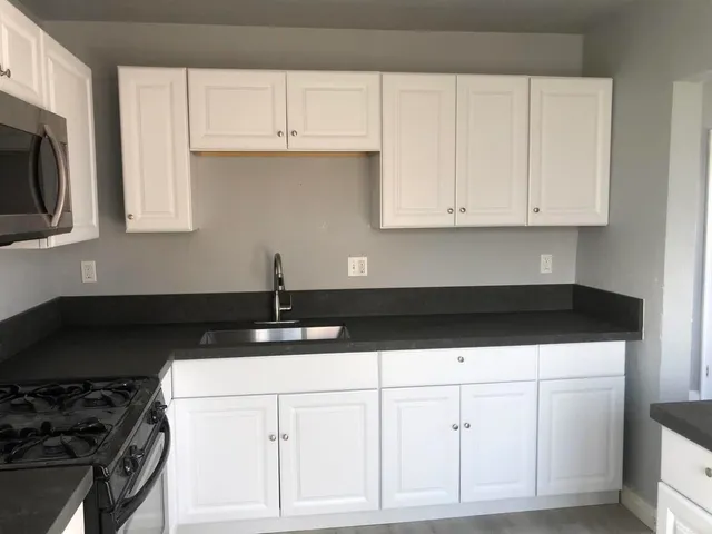 a kitchen with white cabinets and black appliances