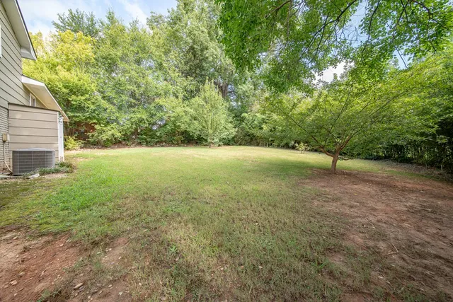 a view of a house with backyard and trees