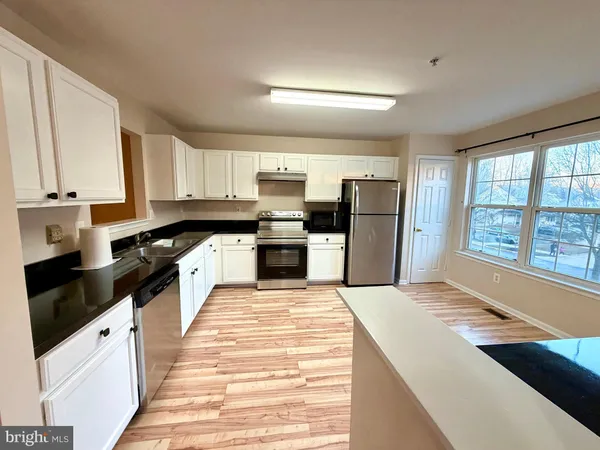 a kitchen with white cabinets and refrigerator