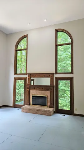 an empty room with windows a fireplace and a grill
