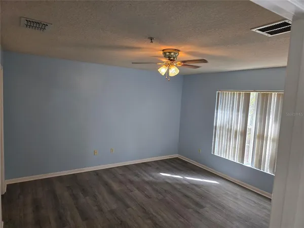 an empty room with windows and chandelier fan