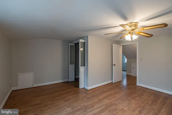 an empty room with wooden floor chandelier fan and windows