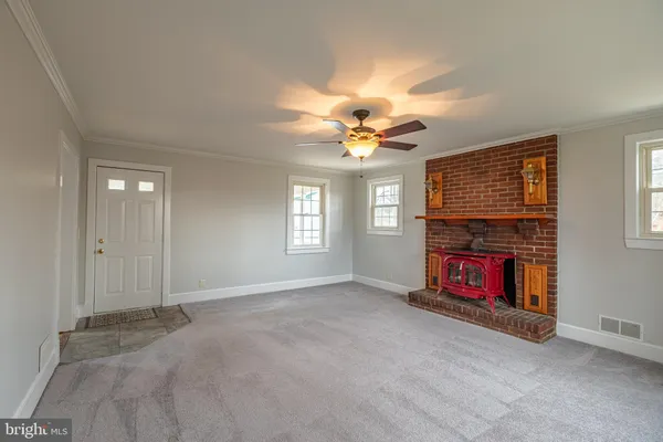 an empty room with windows fireplace and fans