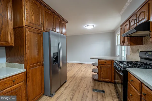 a kitchen with stainless steel appliances granite countertop a refrigerator a stove and a sink with wooden cabinets