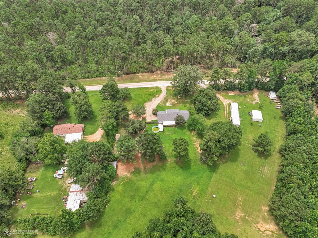 1426 Caney Lake Road Minden, LA 71055 - Photo 35 of 36 Expansive rural property featuring a main residence with a gray shingle roof, multiple outbuildings, and a large grassy area