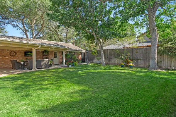 a view of a backyard with table and chairs and a large tree
