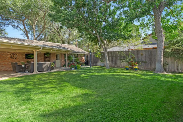 a view of a backyard with table and chairs and a large tree