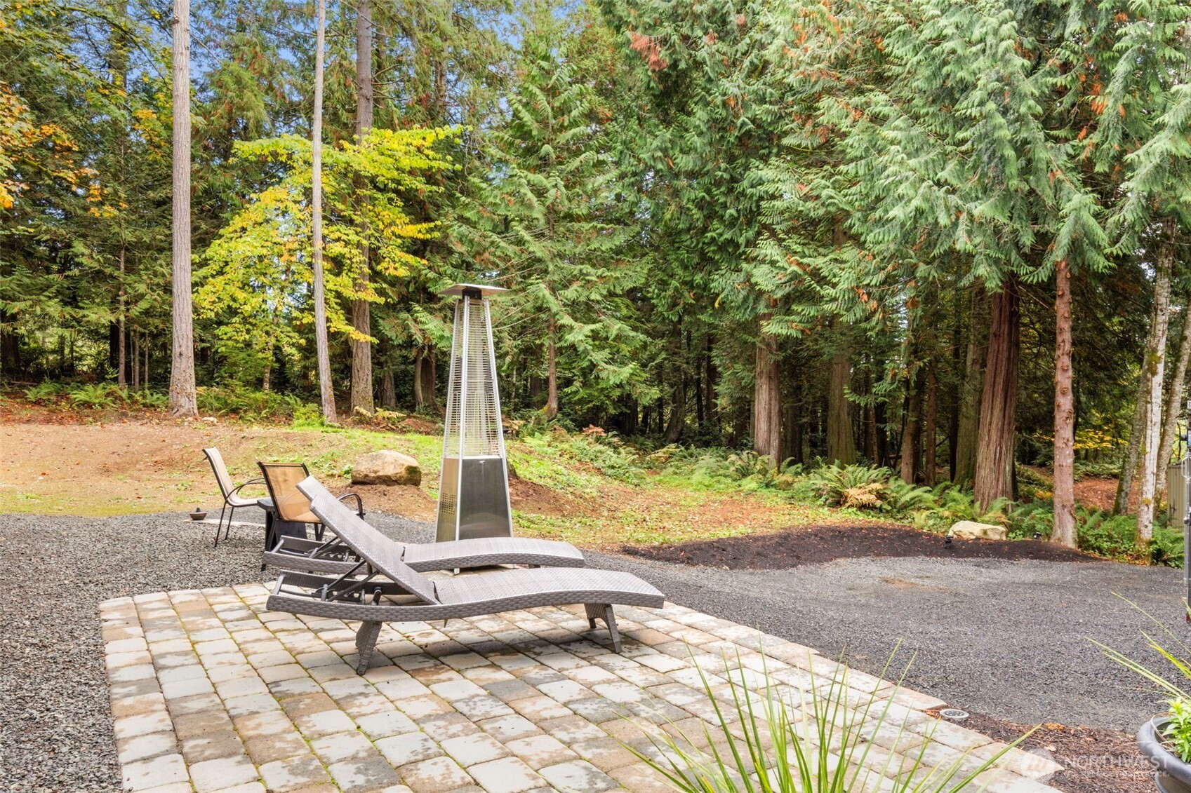 7698 Westerly Lane Northeast Bainbridge Island, WA 98110 - Photo 16 of 28 a view of a patio with a table and chairs under an umbrella
