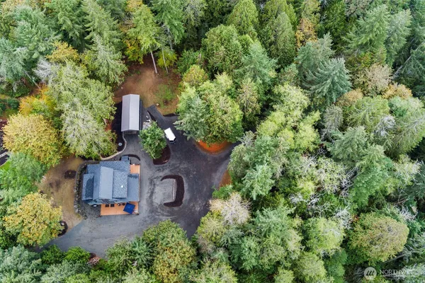 an aerial view of a house with outdoor space and trees all around
