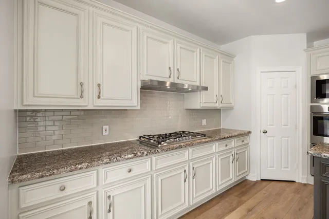 a kitchen with stainless steel appliances granite countertop white cabinets sink and dishwasher
