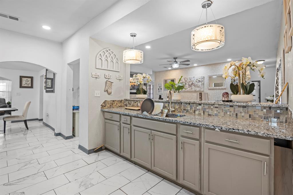 811 Ward Street Marlin, TX 76661 - Photo 8 of 31 Kitchen featuring arched walkways, gray cabinetry, ceiling fan, light marble finish floors, and light stone countertops