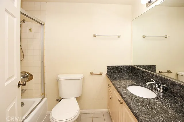a bathroom with a granite countertop sink toilet a mirror and shower