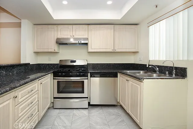 a kitchen with stainless steel appliances granite countertop a sink and a stove