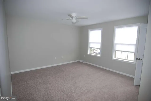 an empty room with a window and a fan