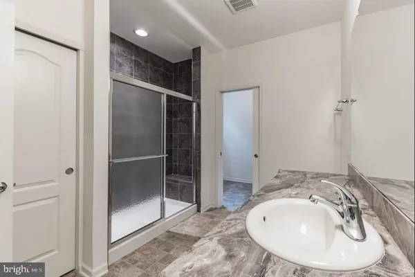 a view of a hallway with wooden floor and a bathroom