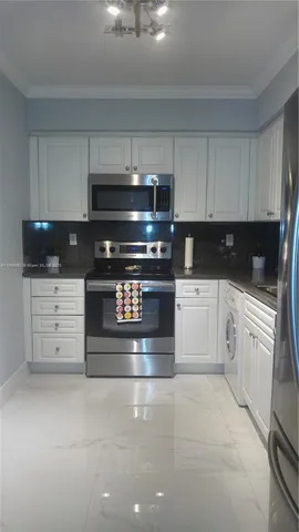 a kitchen with granite countertop a stove and white cabinets