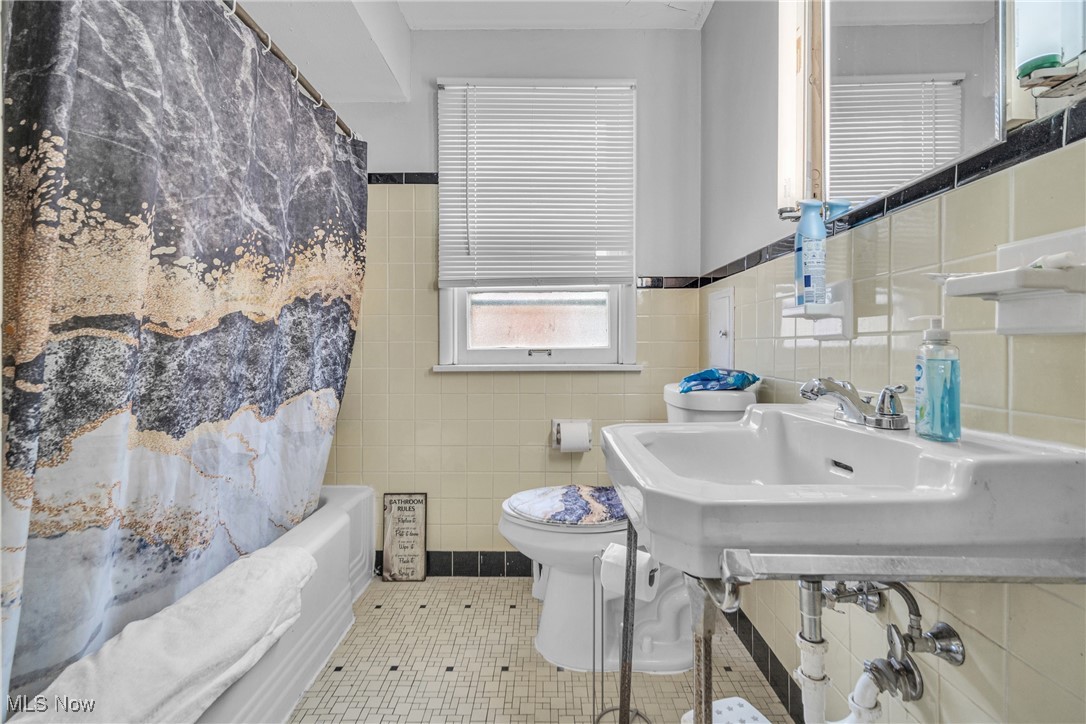 2307 Noble Road Cleveland, OH 44121 - Photo 15 of 29 Bathroom with decorative backsplash, tile patterned floors, toilet, tile walls, and shower / tub combo