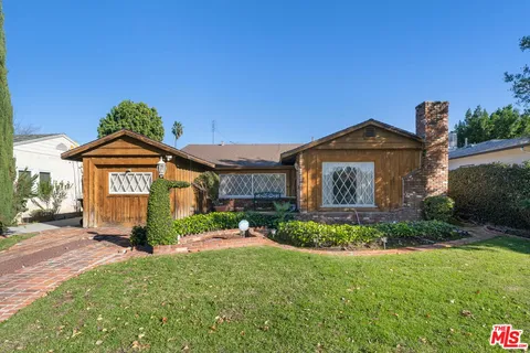 a front view of a house with a yard and potted plants