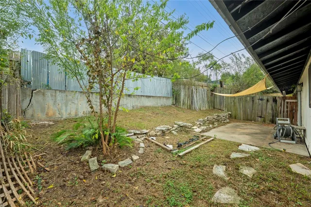 a view of a backyard with table and chairs under an umbrella with wooden fence