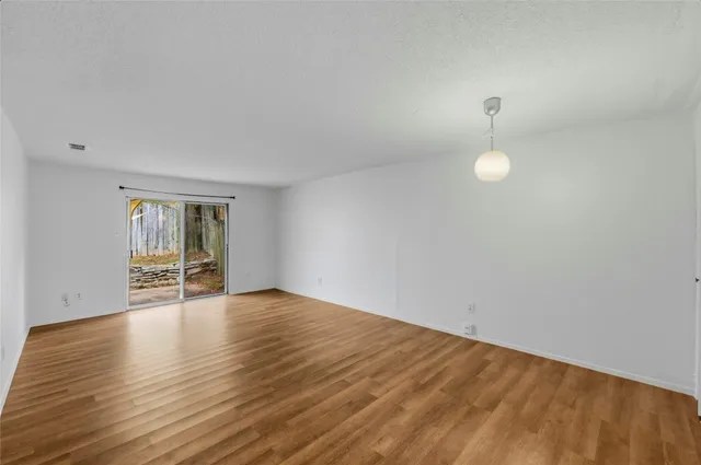 a view of an empty room with wooden floor and window