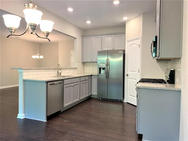 a kitchen with stainless steel appliances granite countertop a sink a stove a refrigerator and island with wooden floor