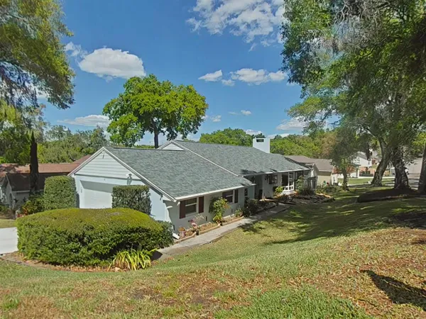 a aerial view of a house with a yard and large trees