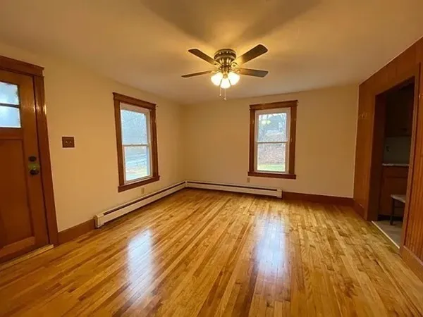 a view of empty room with wooden floor and fan