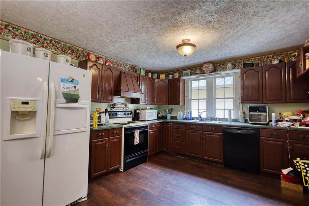 5011 Penfield Road Union Point, GA 30669 - Photo 25 of 68 a kitchen with stainless steel appliances granite countertop a refrigerator a sink dishwasher a stove and white countertops with wooden floor