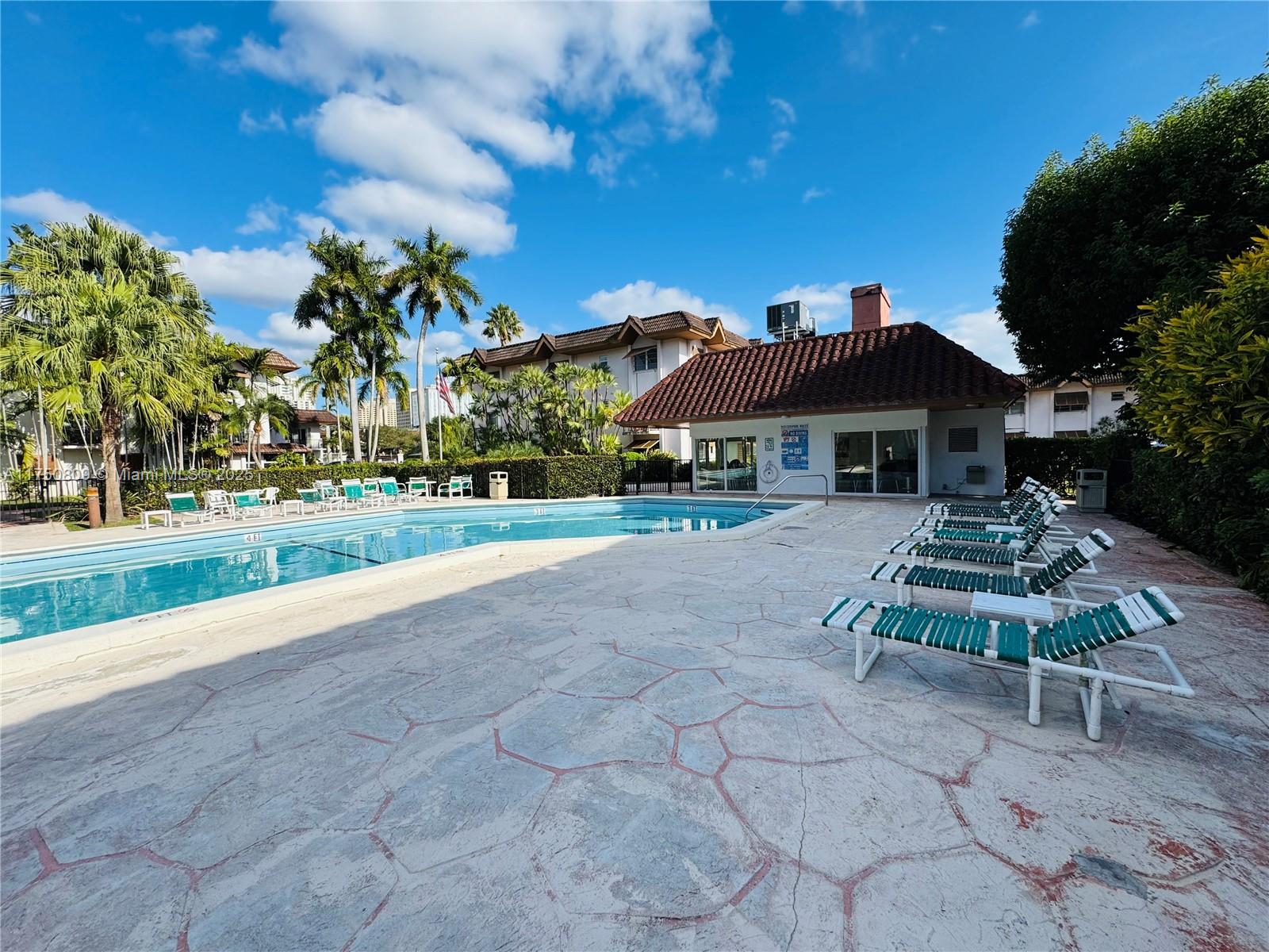 9394 Southwest 77th Avenue, Unit F1 Miami, FL 33156 - Photo 15 of 24 a view of a patio with table and chairs under an umbrella