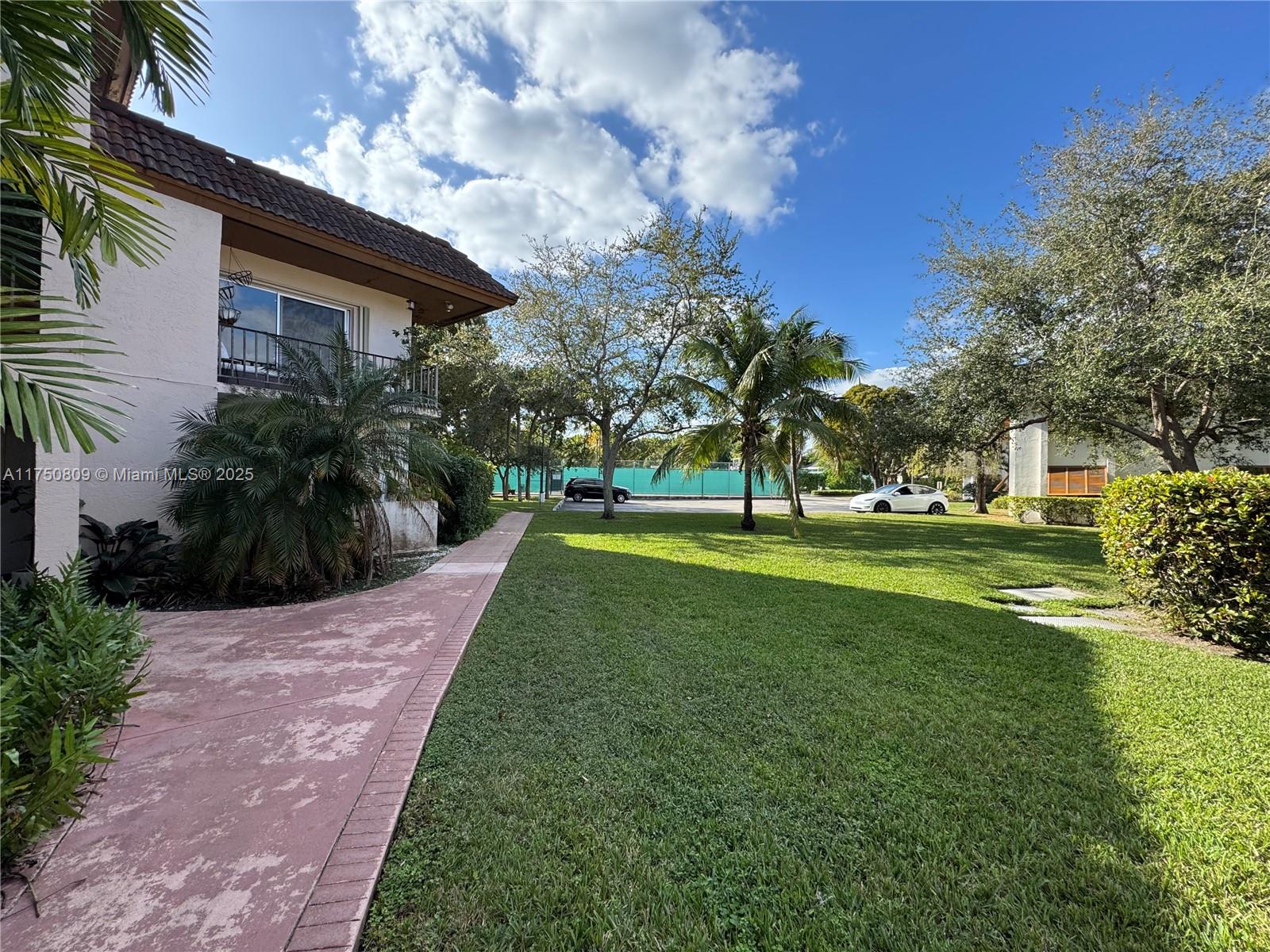 9394 Southwest 77th Avenue, Unit F1 Miami, FL 33156 - Photo 17 of 24 a front view of a house with a yard