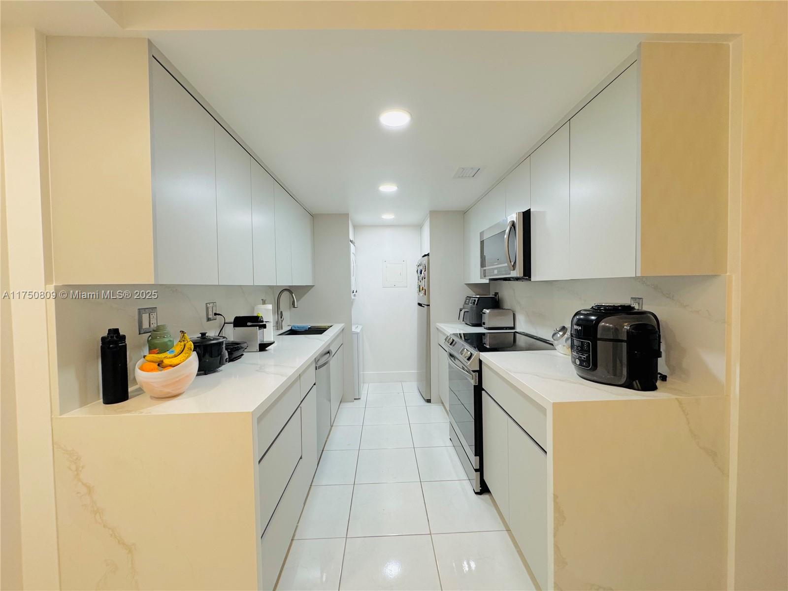 9394 Southwest 77th Avenue, Unit F1 Miami, FL 33156 - Photo 2 of 24 a kitchen that has a sink and a stove in it