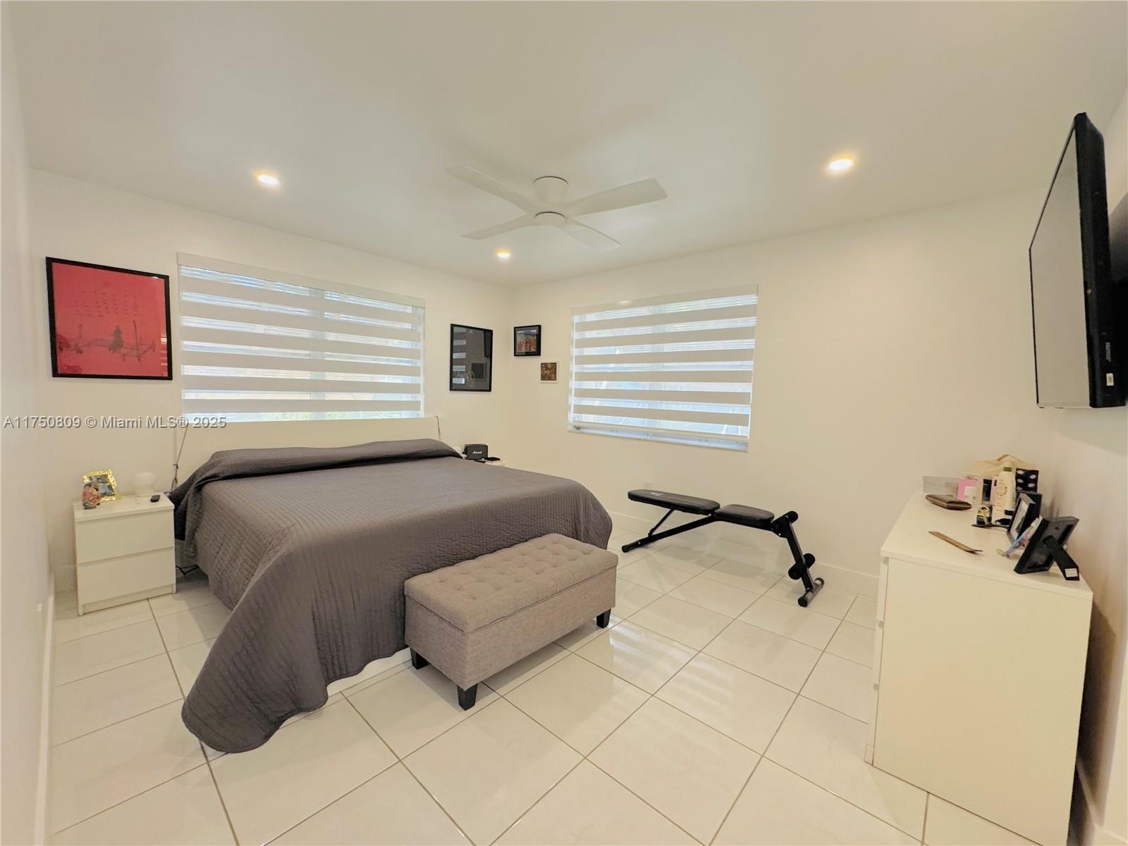 9394 Southwest 77th Avenue, Unit F1 Miami, FL 33156 - Photo 9 of 24 a bedroom with bed and a flat tv screen on dresser