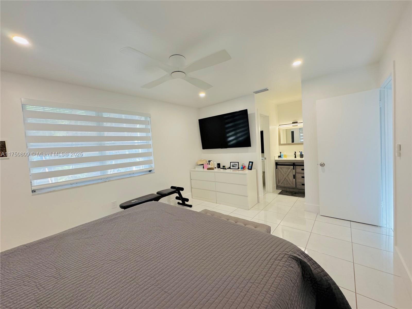 9394 Southwest 77th Avenue, Unit F1 Miami, FL 33156 - Photo 10 of 24 a bedroom with a bed and a flat screen tv
