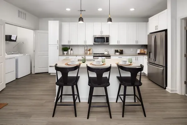 a kitchen with stainless steel appliances kitchen island granite countertop a table chairs microwave and sink