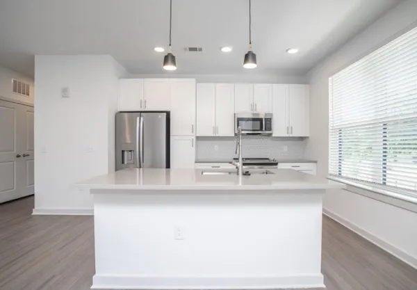 a kitchen with stainless steel appliances granite countertop a sink a refrigerator and a granite counter tops with wooden floors