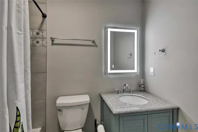 a bathroom with a granite countertop toilet sink and mirror