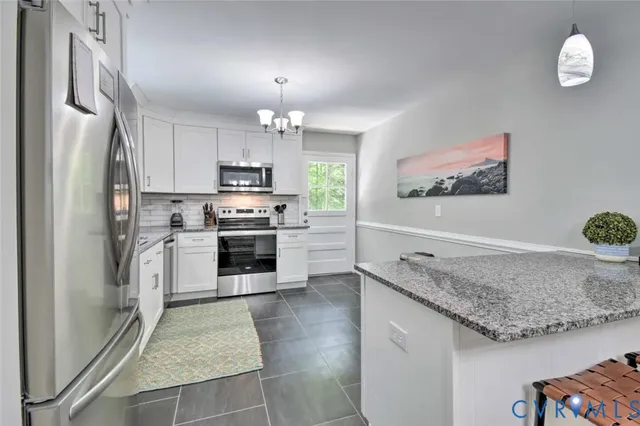 a kitchen with granite countertop a refrigerator a stove a sink a microwave oven with cabinets and wooden floor