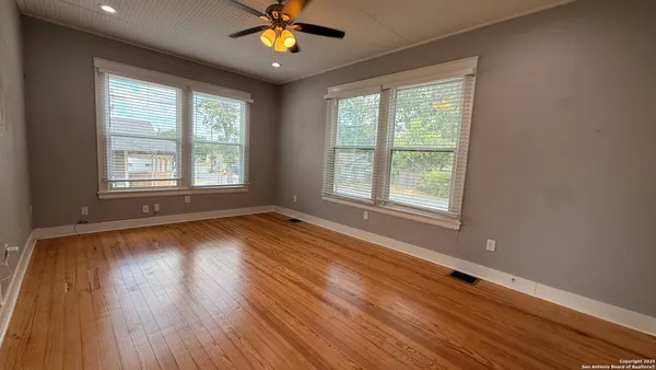 a view of an empty room with wooden floor and a window