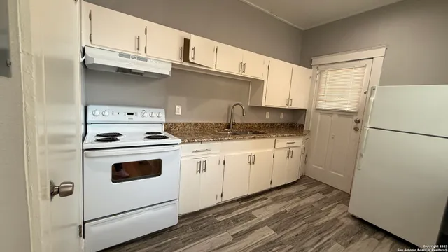 a kitchen with granite countertop cabinets appliances and a counter space