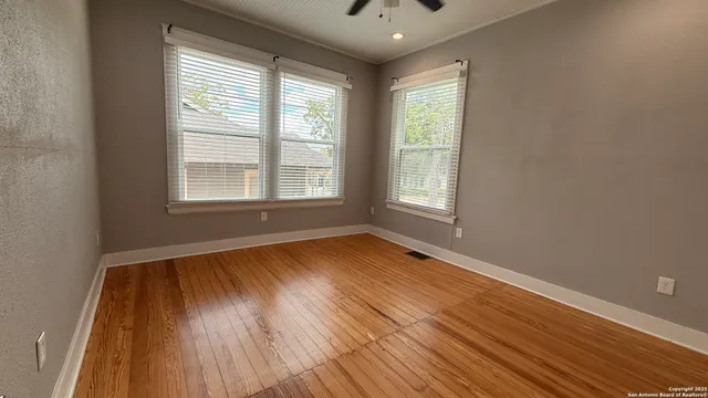 an empty room with wooden floor and windows