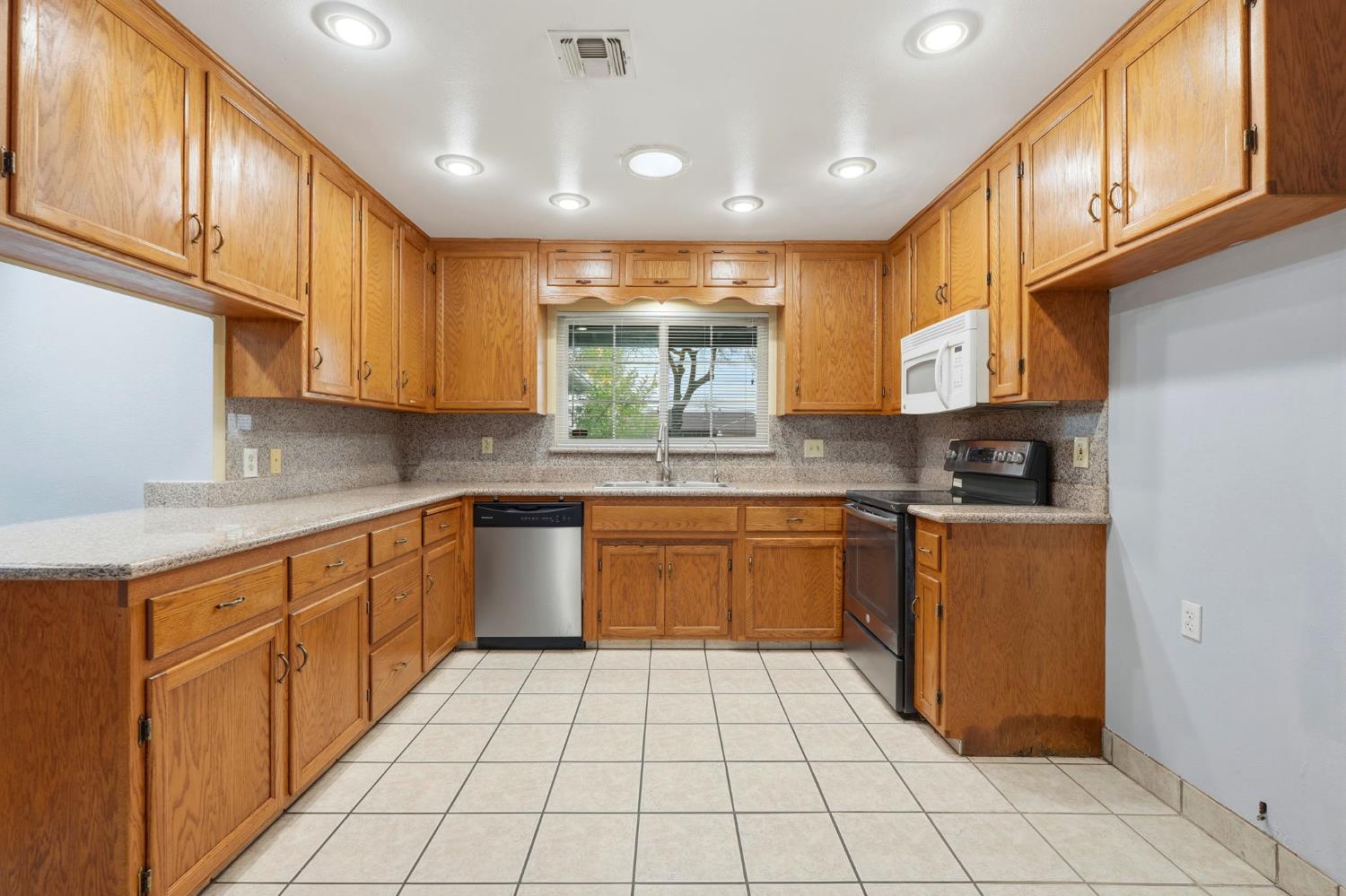 2826 East Hampton Way Fresno, CA 93726 - Photo 8 of 33 a kitchen with stainless steel appliances granite countertop a refrigerator and sink
