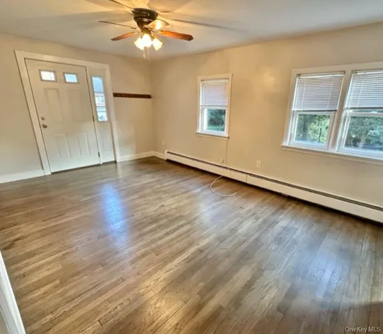 a view of an empty room with wooden floor and a window