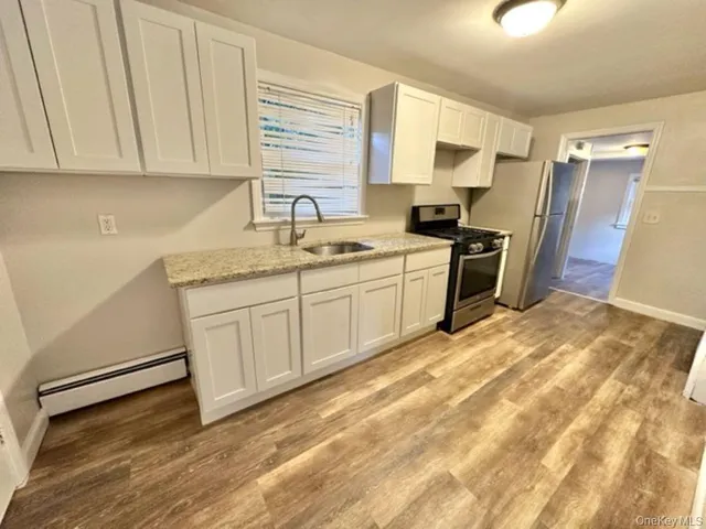 a kitchen with stainless steel appliances granite countertop a sink a stove a refrigerator with grey cabinets