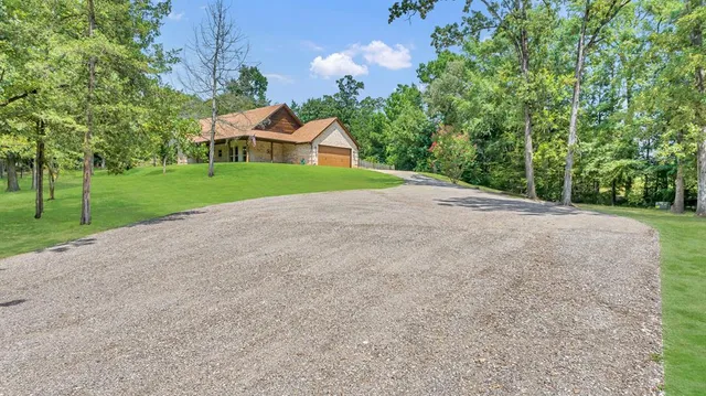 a view of a house with a yard and large trees